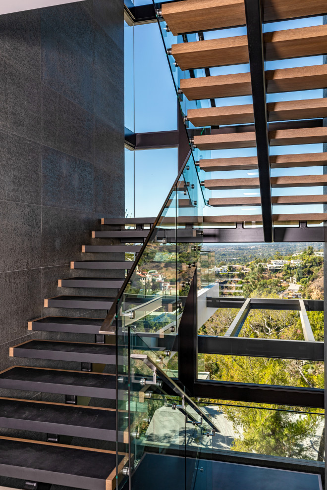 This is an example of a contemporary floating glass railing staircase in Orange County with open risers.