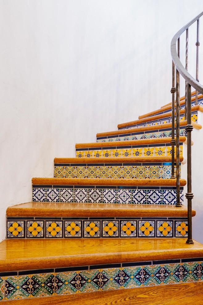 Idées déco pour un escalier courbe méditerranéen de taille moyenne avec des marches en bois, des contremarches carrelées et un garde-corps en métal.