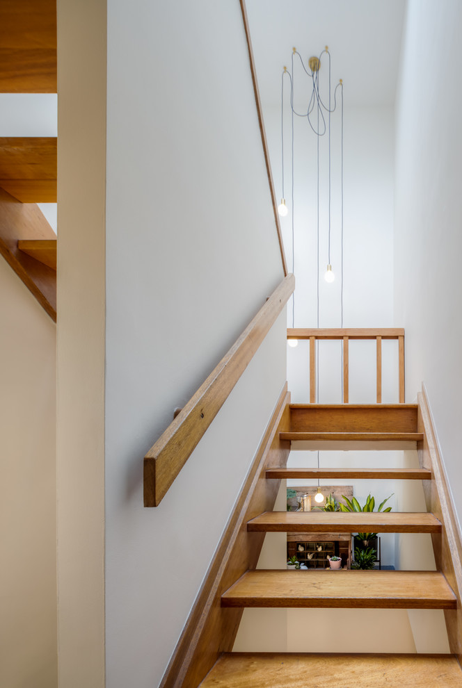 На фото: лестница на больцах, среднего размера в скандинавском стиле с деревянными ступенями и деревянными перилами без подступенок с