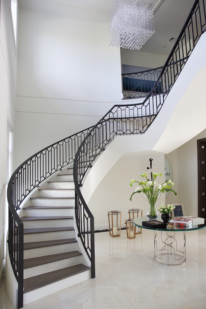 Свежая идея для дизайна: большая изогнутая лестница в стиле неоклассика (современная классика) с деревянными ступенями и крашенными деревянными подступенками - отличное фото интерьера