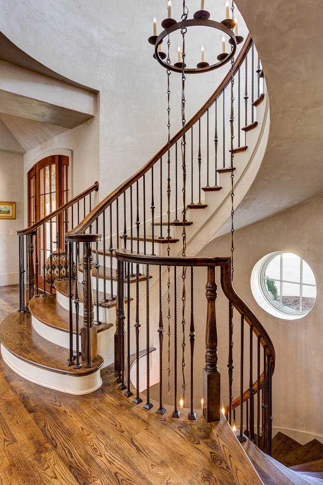 Classic wood curved staircase in Other with painted wood risers.