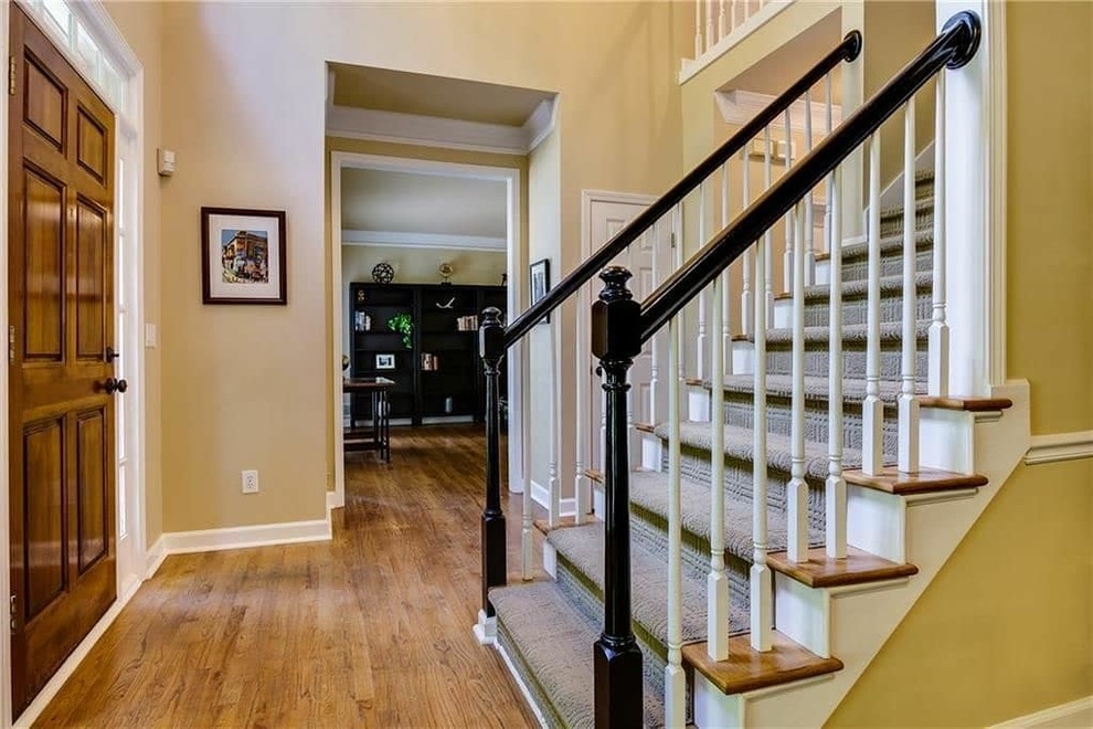 На фото: прямая лестница среднего размера в стиле неоклассика (современная классика) с ступенями с ковровым покрытием, крашенными деревянными подступенками и деревянными перилами