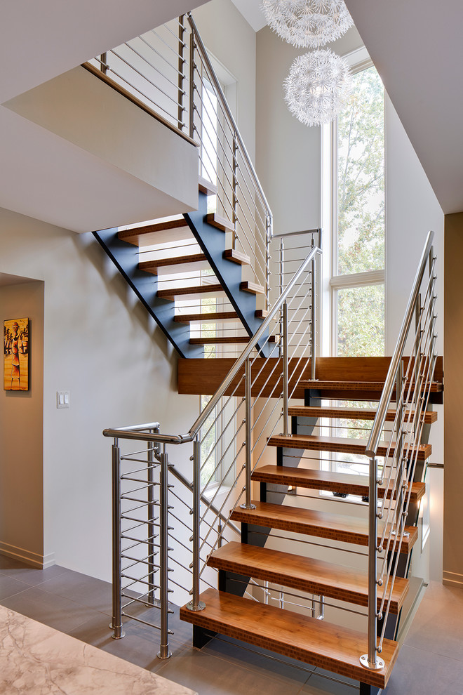 Свежая идея для дизайна: п-образная лестница среднего размера в современном стиле с деревянными ступенями и металлическими перилами без подступенок - отличное фото интерьера