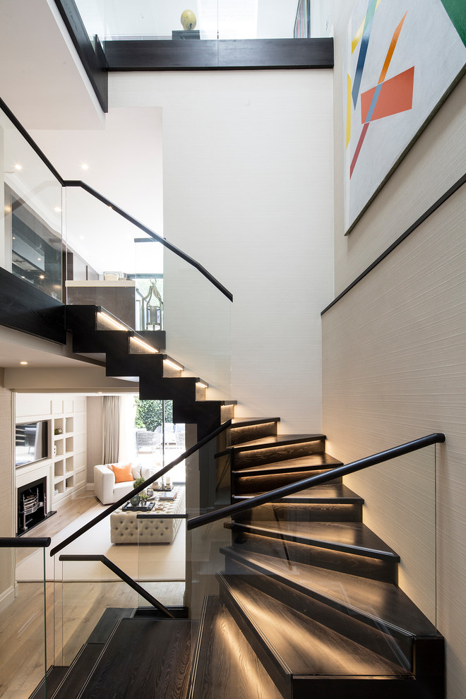 This is an example of a medium sized contemporary wood u-shaped glass railing staircase in London with wood risers.