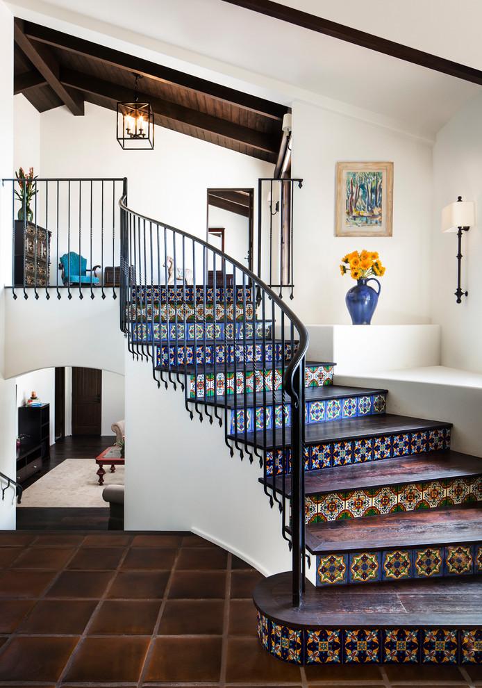 Foto de escalera curva tradicional de tamaño medio con escalones de madera, contrahuellas con baldosas y/o azulejos y barandilla de metal