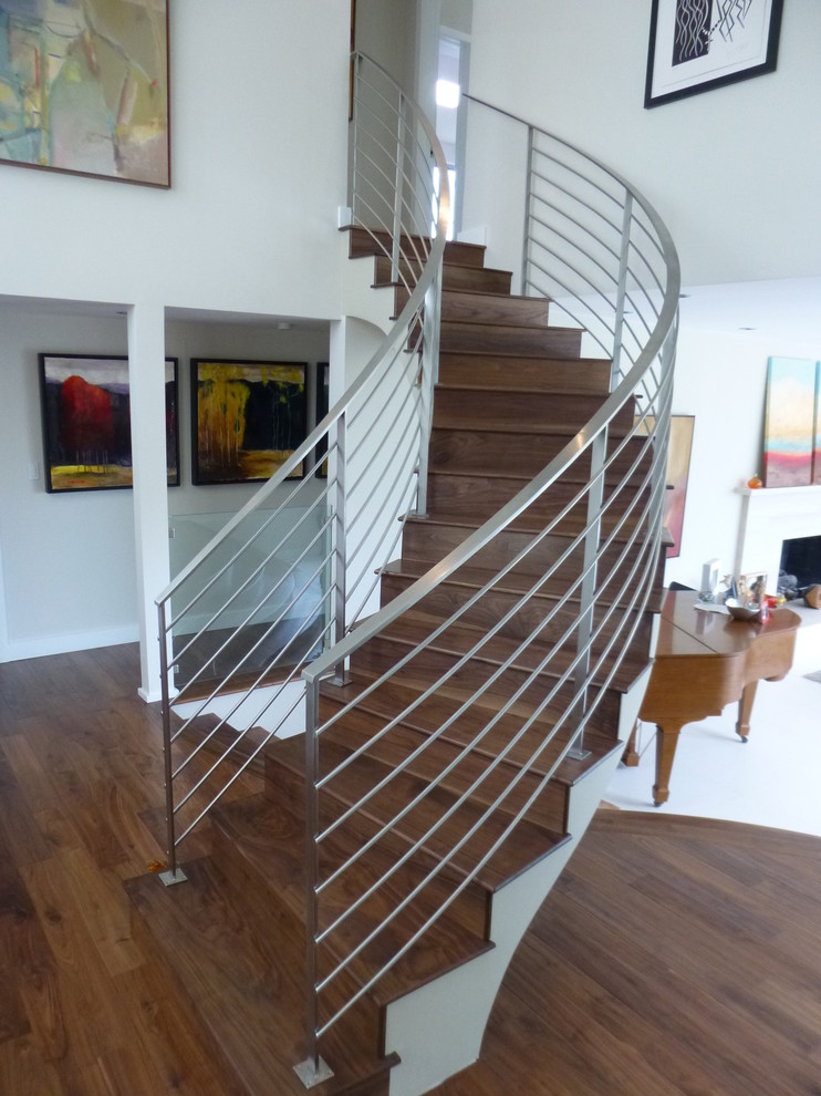 Ejemplo de escalera curva contemporánea con escalones de madera y contrahuellas de madera