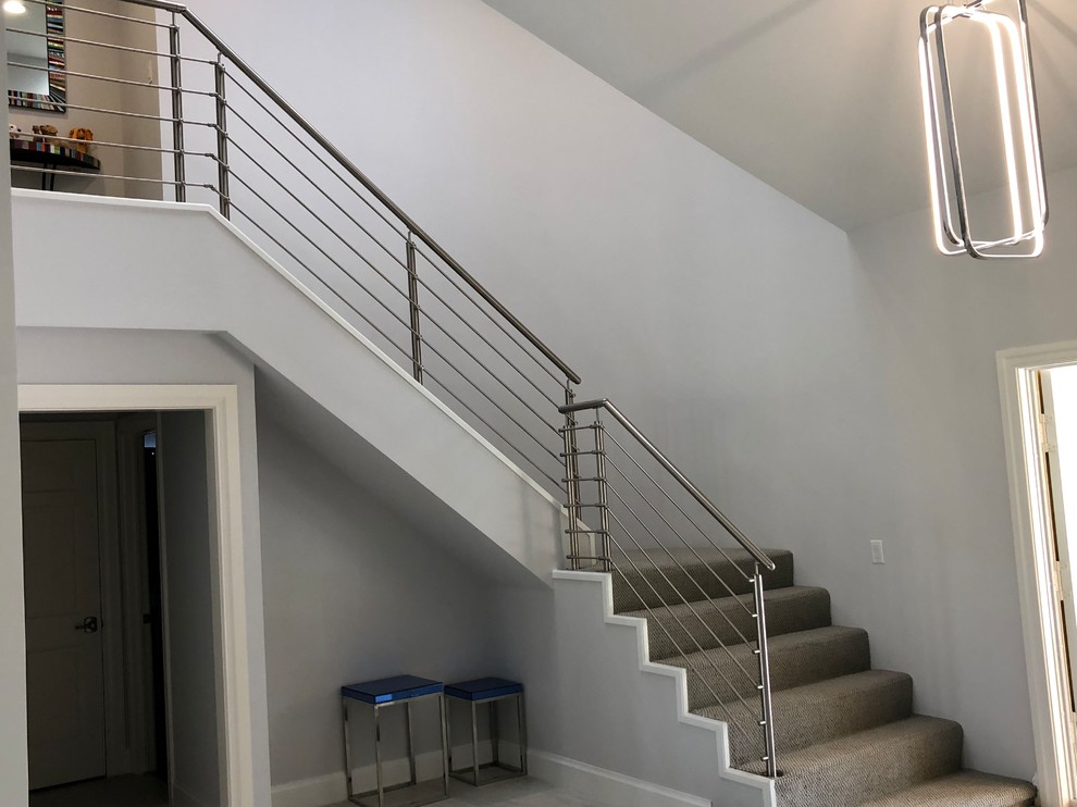 На фото: угловая лестница среднего размера в стиле лофт с ступенями с ковровым покрытием, ковровыми подступенками и металлическими перилами