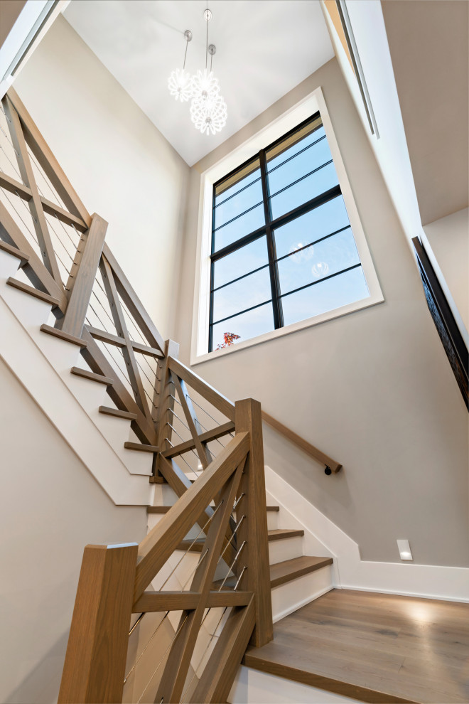 На фото: п-образная лестница среднего размера в стиле неоклассика (современная классика) с деревянными ступенями, крашенными деревянными подступенками и перилами из смешанных материалов