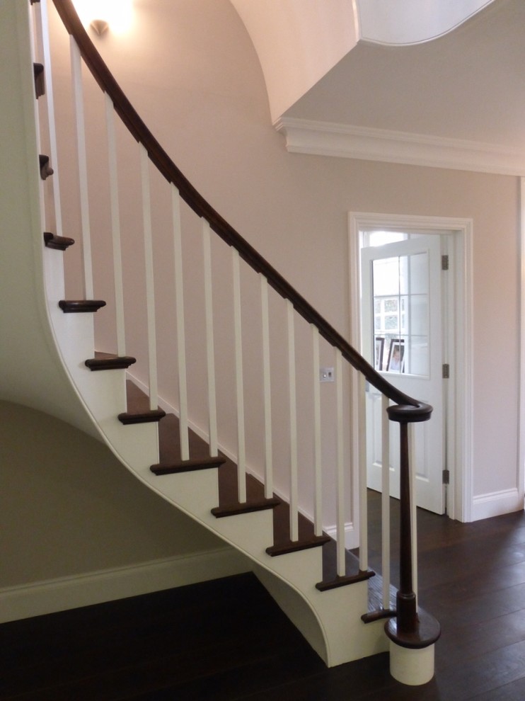 Cette image montre un très grand escalier peint courbe design avec des marches en bois.