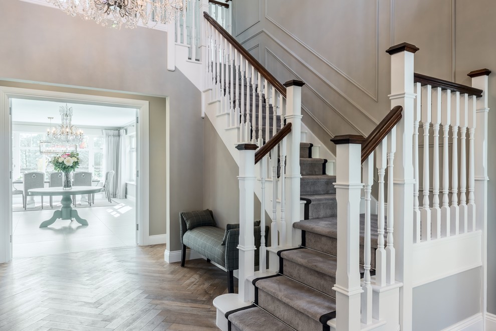 Стильный дизайн: огромная угловая лестница в классическом стиле с крашенными деревянными подступенками, деревянными перилами и крашенными деревянными ступенями - последний тренд