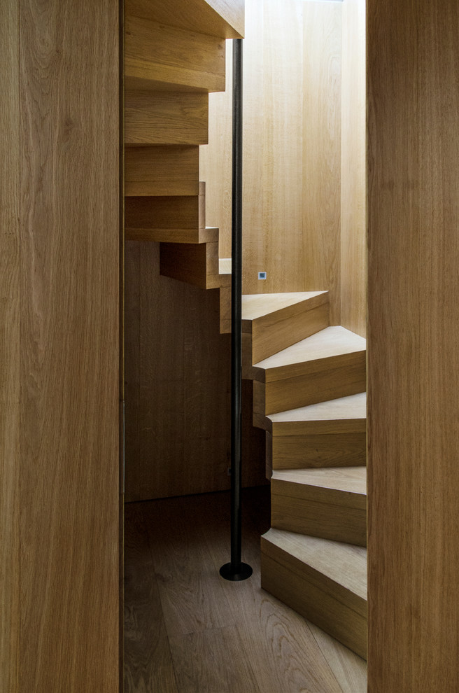 Example of a trendy wooden curved staircase design in London with wooden risers