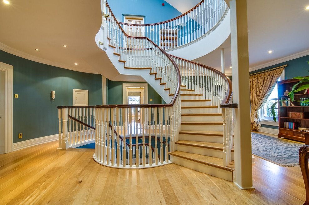 Diseño de escalera curva clásica extra grande con escalones de madera y contrahuellas de madera pintada
