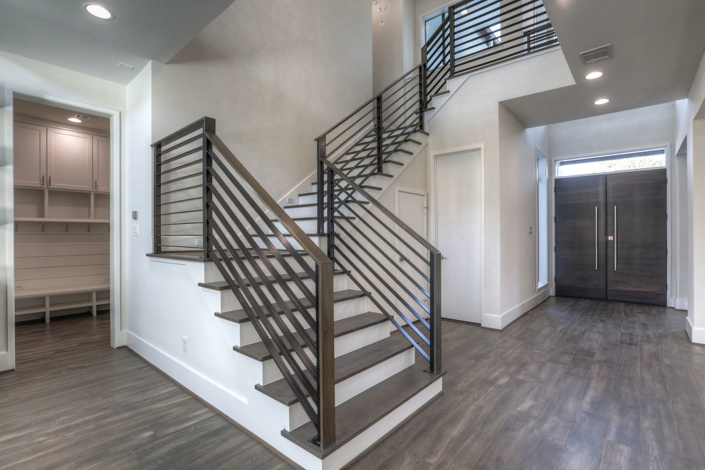 Large modern wood u-shaped metal railing staircase in Houston with painted wood risers.