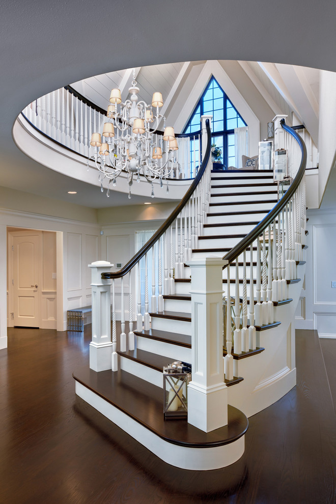 Large elegant wooden curved staircase photo in Cleveland with painted risers