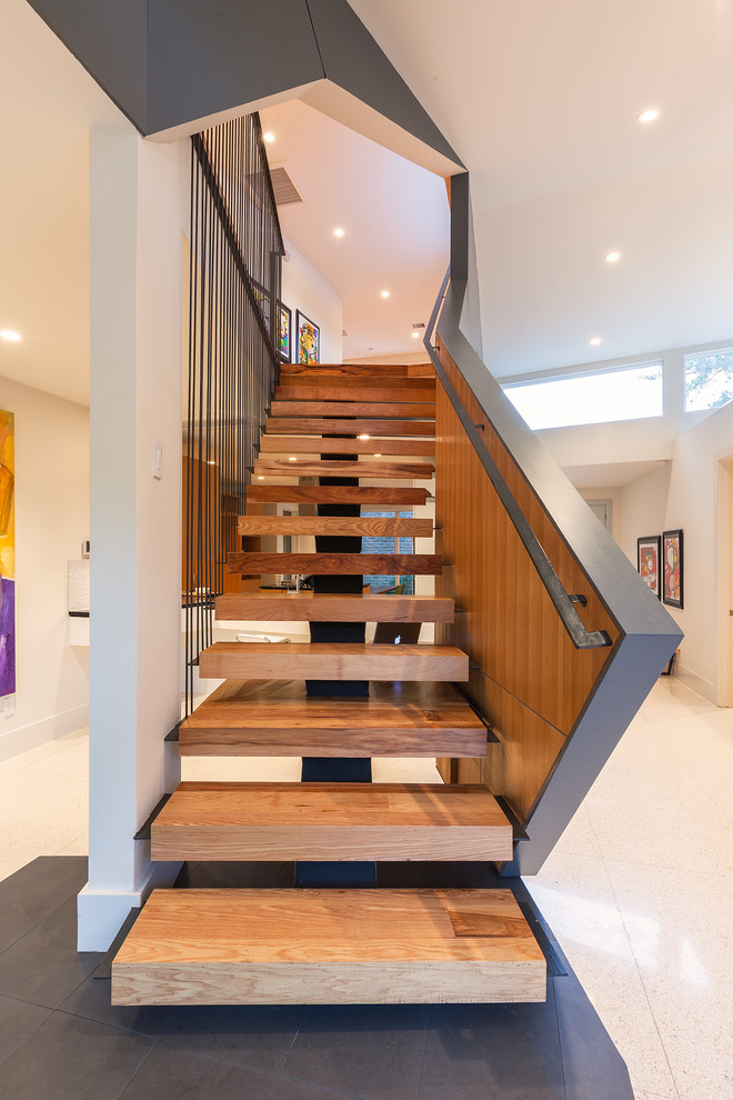 Cette photo montre un grand escalier sans contremarche droit tendance avec des marches en bois et un garde-corps en métal.