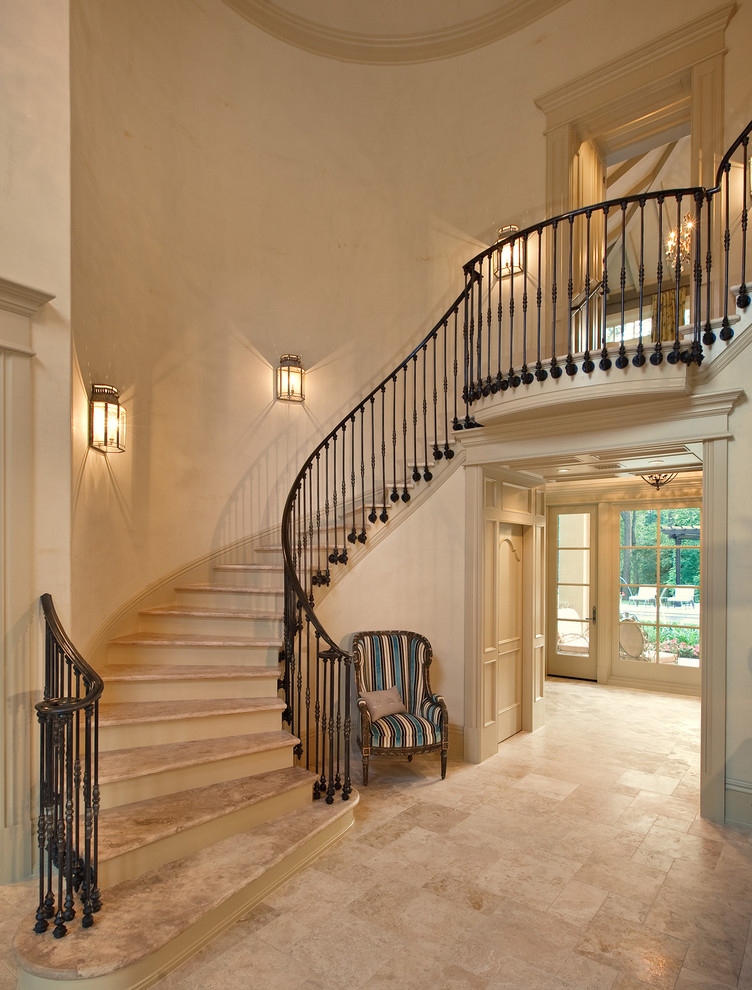 Photo of a large mediterranean curved staircase in Houston with travertine treads and painted wood risers.