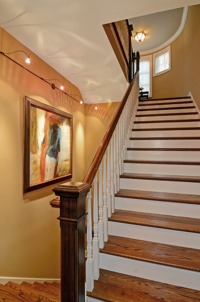 Imagen de escalera en U clásica de tamaño medio con escalones de madera, contrahuellas de madera pintada y barandilla de madera