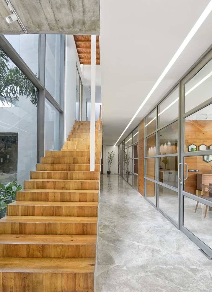 This is an example of a contemporary wood straight staircase in Ahmedabad with wood risers.