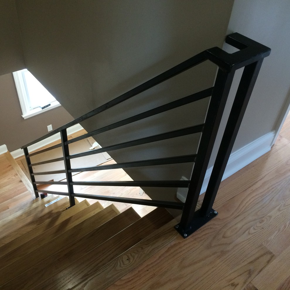 Cette photo montre un escalier droit tendance de taille moyenne avec des marches en bois, des contremarches en bois et un garde-corps en métal.