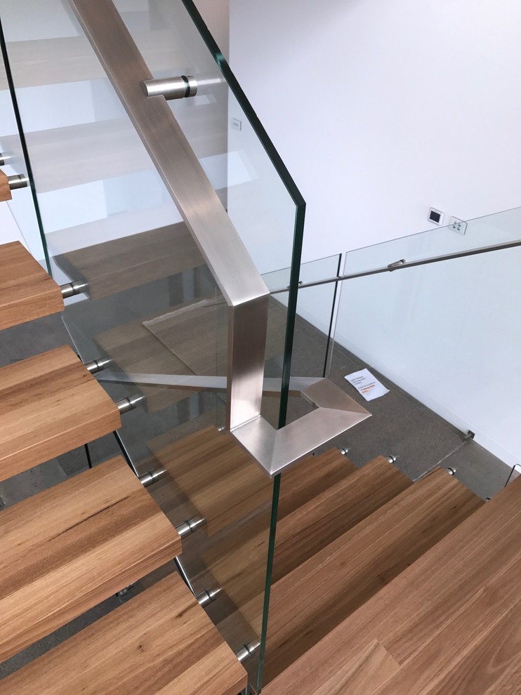 Пример оригинального дизайна: изогнутая лестница среднего размера в стиле лофт с деревянными ступенями и стеклянными перилами
