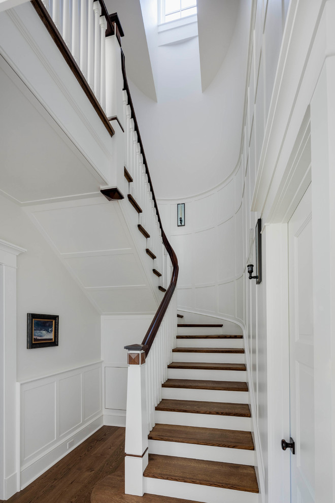 Cette photo montre un grand escalier peint courbe chic avec des marches en bois et un garde-corps en bois.