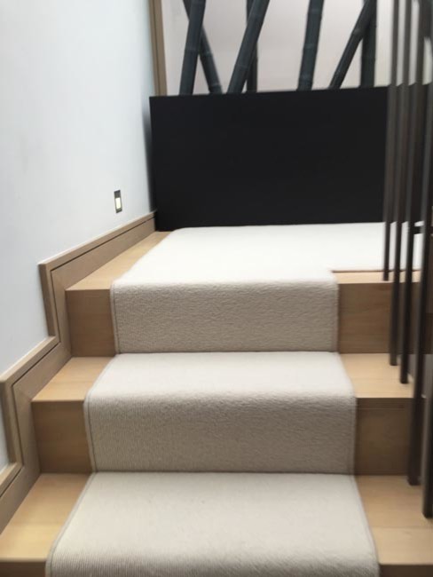 На фото: изогнутая лестница в стиле неоклассика (современная классика) с ступенями с ковровым покрытием и ковровыми подступенками