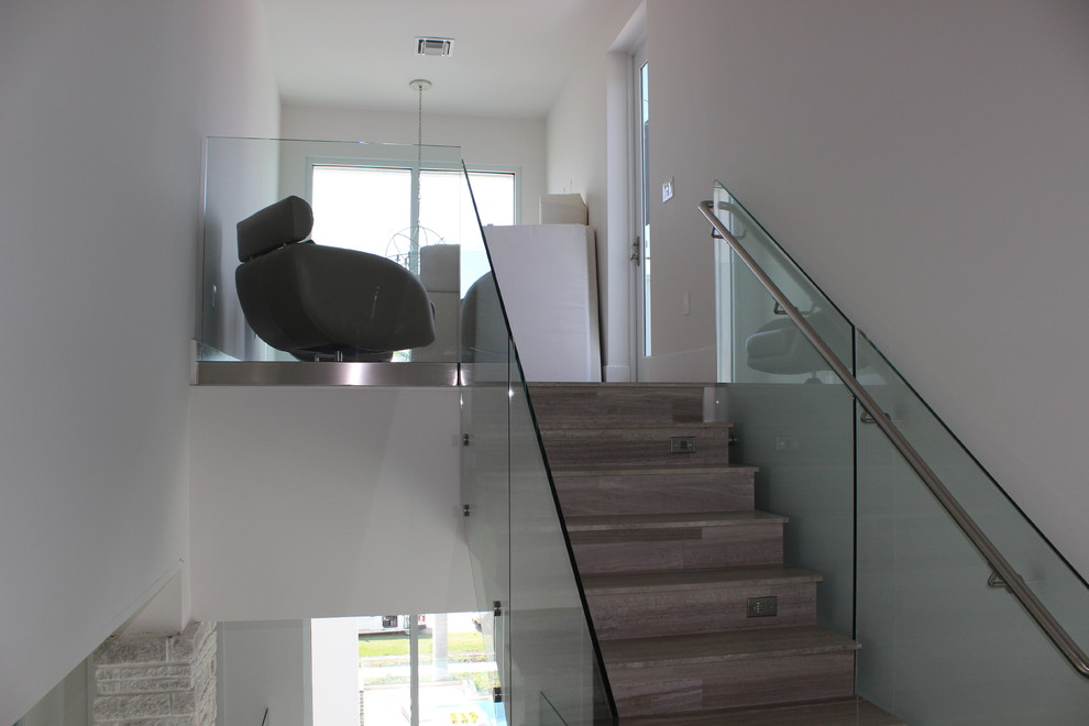 Idée de décoration pour un escalier carrelé design de taille moyenne avec des contremarches carrelées et un garde-corps en métal.