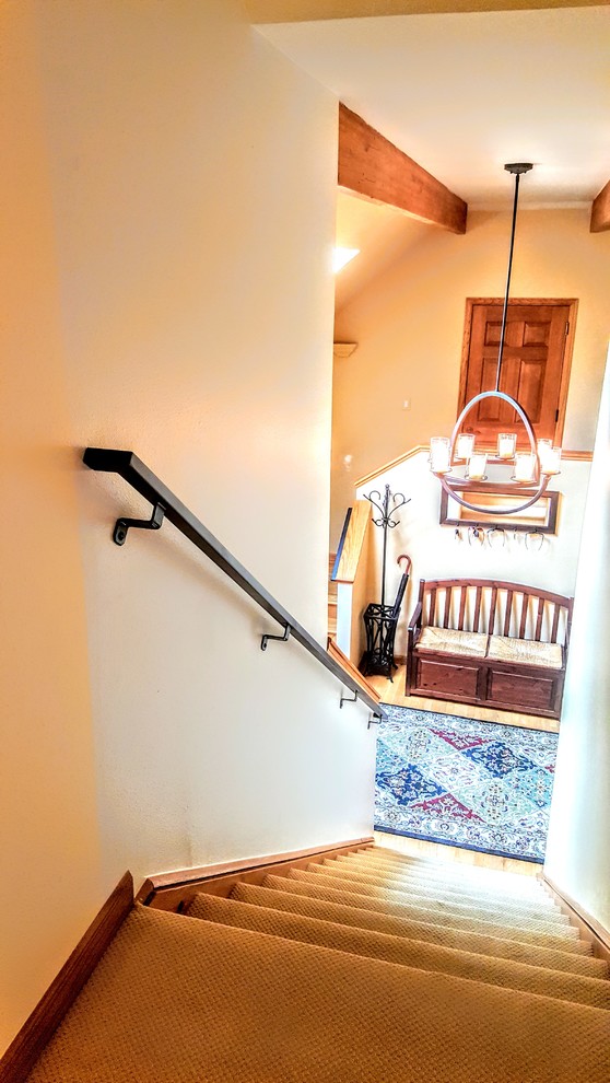 Imagen de escalera recta tradicional de tamaño medio con escalones enmoquetados, barandilla de metal y contrahuellas enmoquetadas