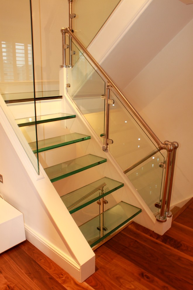 Стильный дизайн: большая лестница на больцах в современном стиле с стеклянными ступенями без подступенок - последний тренд