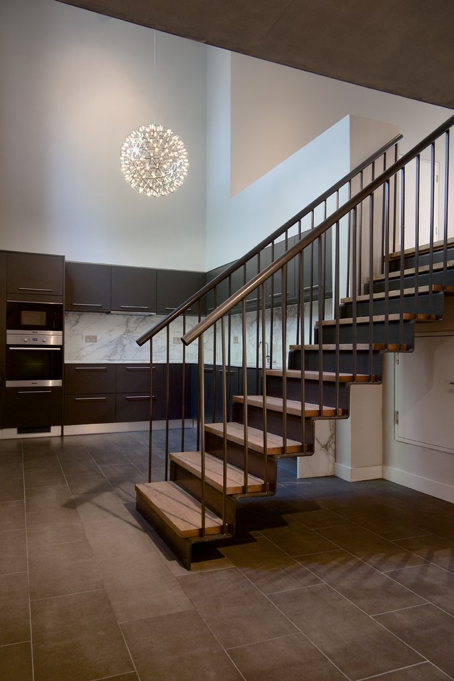 Inspiration for an industrial wooden straight staircase remodel in London with metal risers