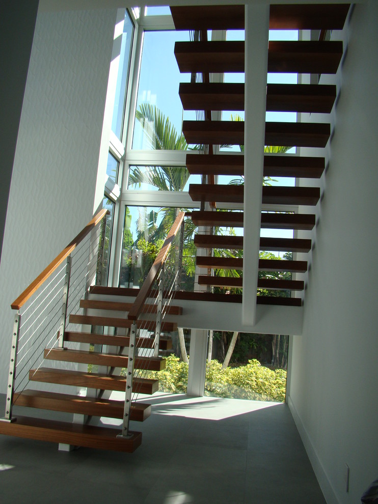 Foto de escalera suspendida actual pequeña con escalones de madera, contrahuellas de metal y barandilla de cable