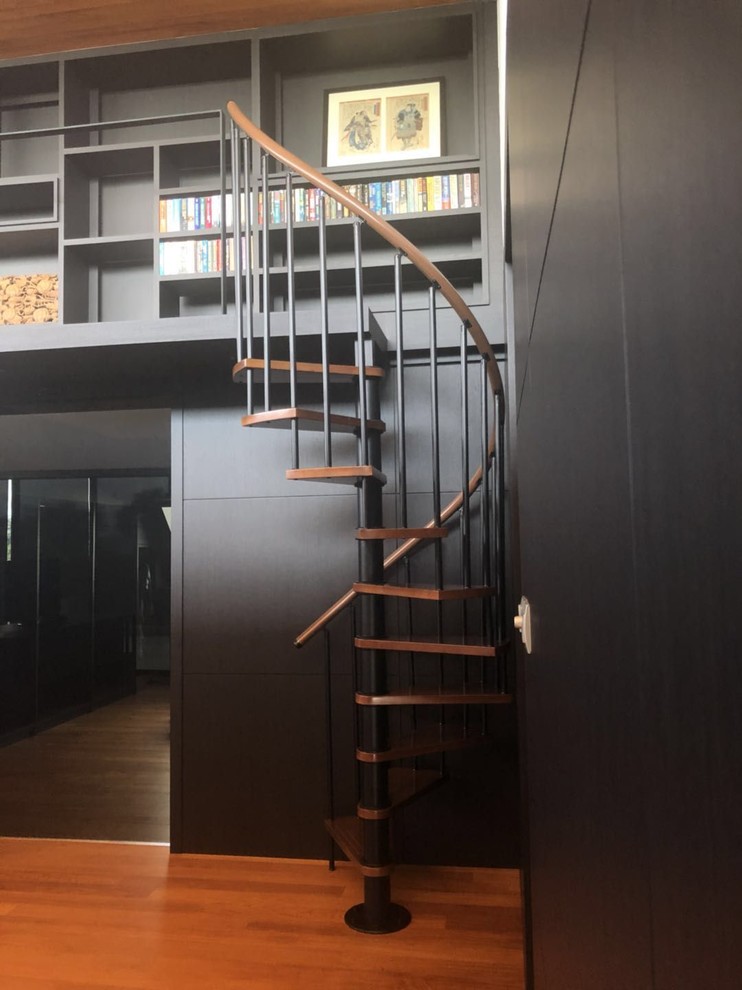Réalisation d'un petit escalier sans contremarche hélicoïdal minimaliste avec des marches en bois et un garde-corps en métal.