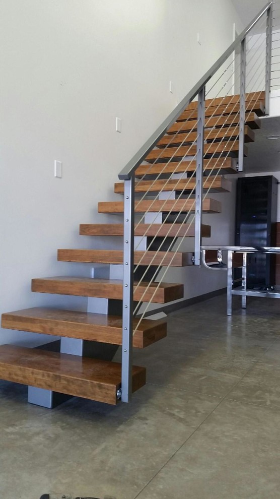 Cette image montre un escalier sans contremarche droit minimaliste de taille moyenne avec des marches en bois et un garde-corps en métal.