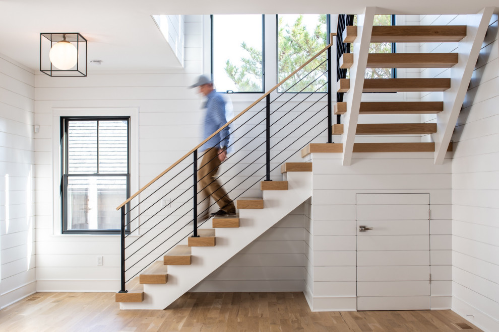 На фото: угловая лестница среднего размера в стиле модернизм с деревянными ступенями, металлическими перилами и стенами из вагонки без подступенок с