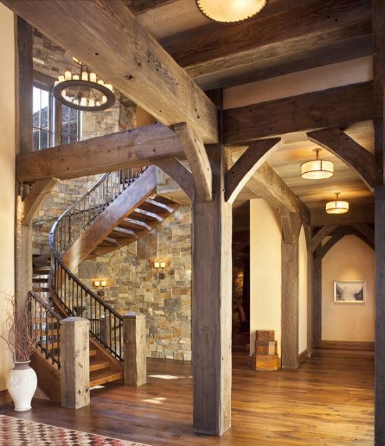 Imagen de escalera curva rústica grande sin contrahuella con escalones de madera y barandilla de metal