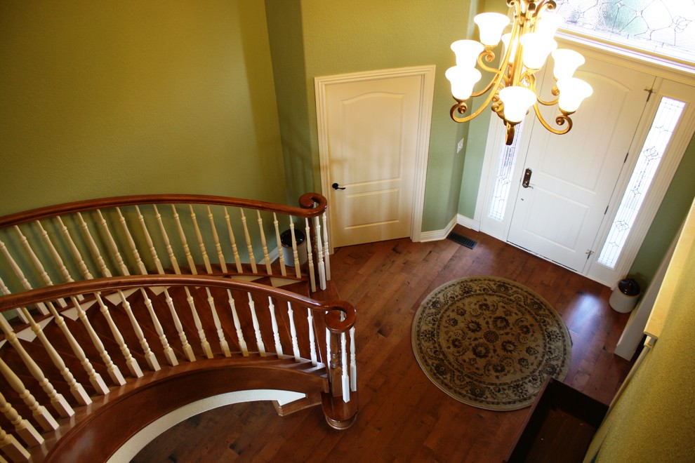 Large traditional wood curved staircase in Other with wood risers.