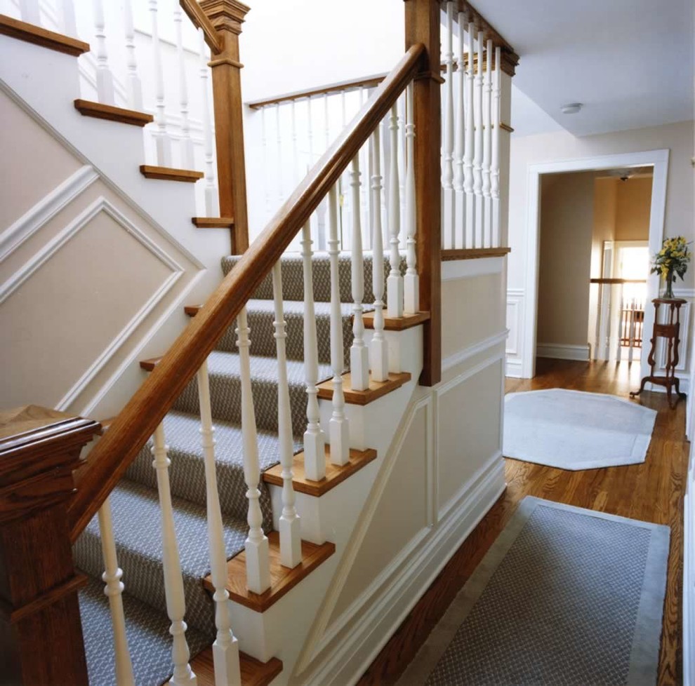 Large classic carpeted u-shaped wood railing staircase in Chicago with carpeted risers.