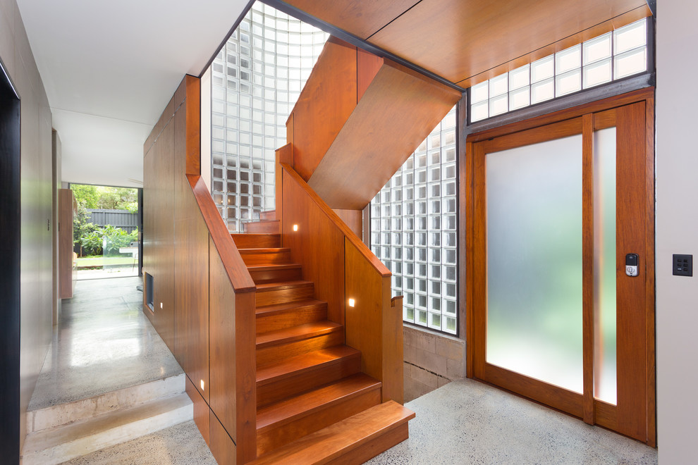 На фото: п-образная деревянная лестница в современном стиле с деревянными ступенями и деревянными перилами с