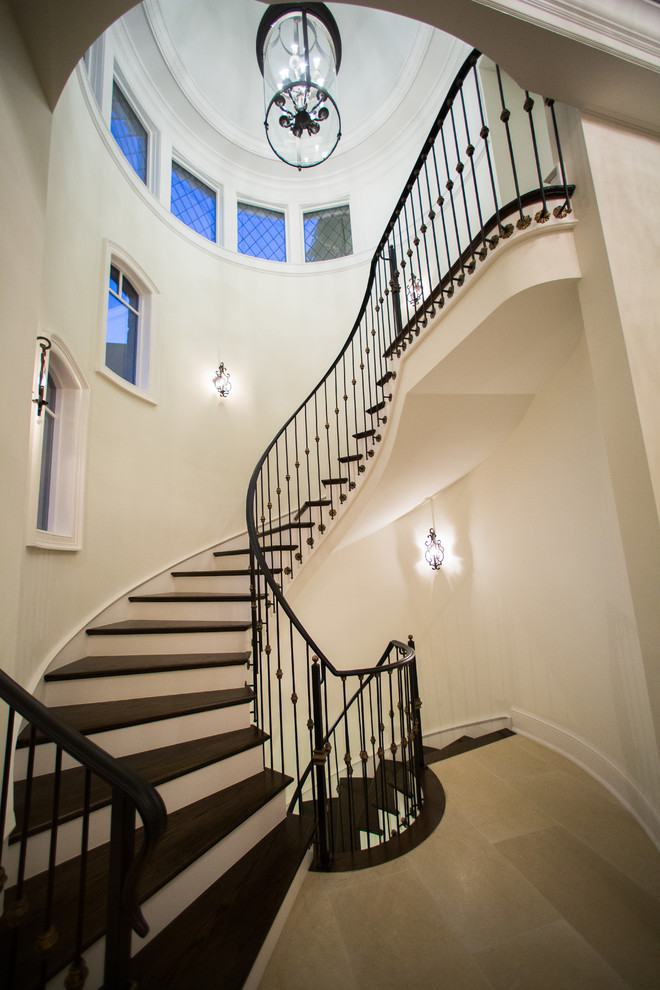На фото: огромная винтовая лестница в классическом стиле с деревянными ступенями, крашенными деревянными подступенками и металлическими перилами