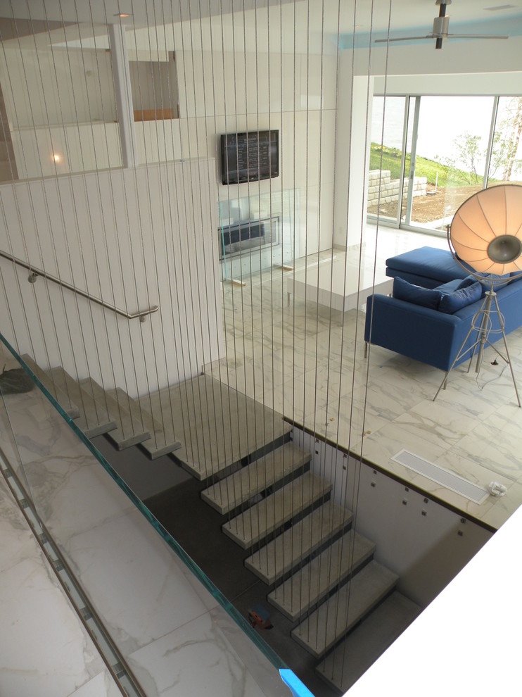 Exempel på en stor modern flytande betongtrappa, med öppna sättsteg och räcke i metall