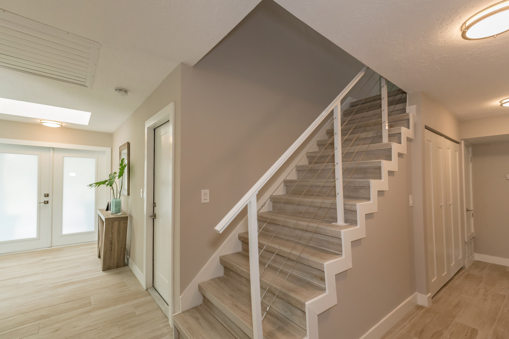 Foto de escalera recta moderna de tamaño medio con escalones con baldosas, contrahuellas con baldosas y/o azulejos y barandilla de metal
