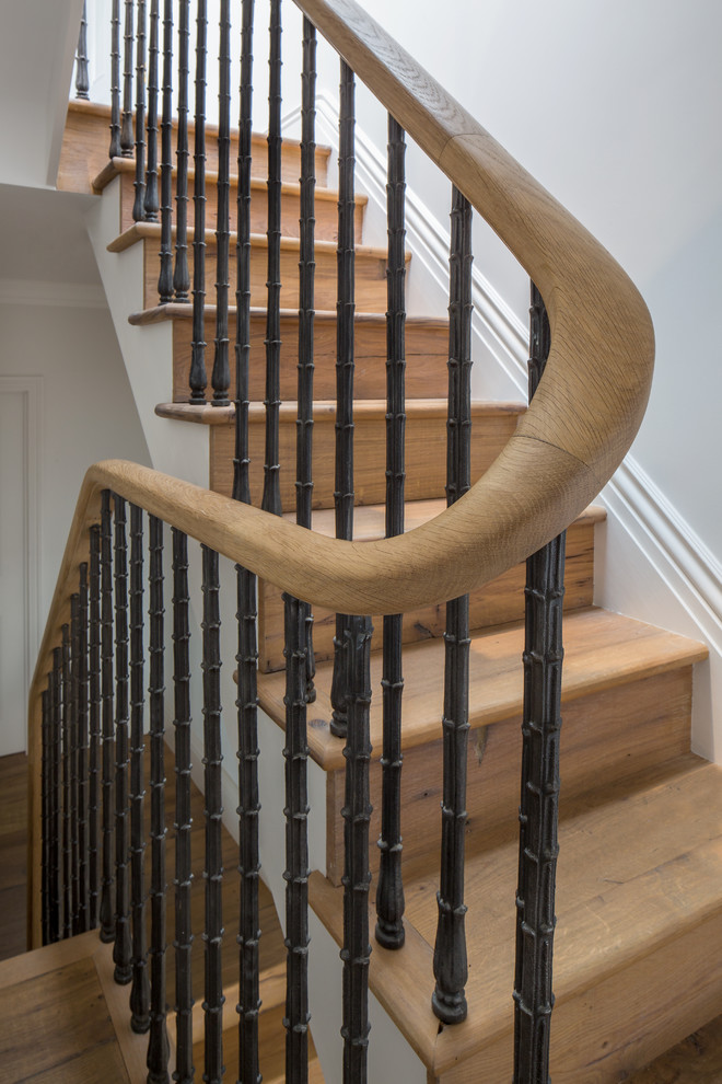 Diseño de escalera de caracol clásica renovada con escalones de madera, contrahuellas de madera y barandilla de metal