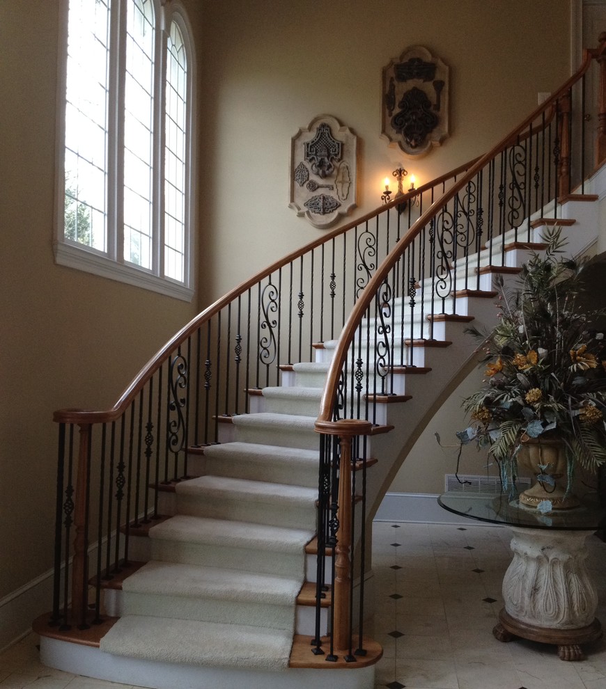 Example of a large classic wooden curved metal railing staircase design in Atlanta with painted risers