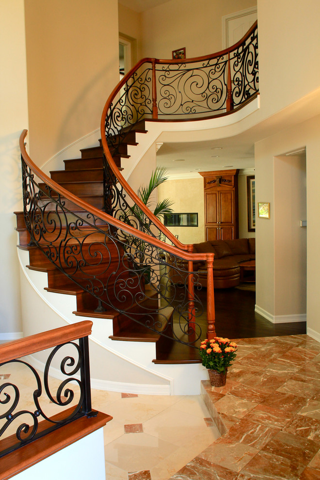Стильный дизайн: изогнутая деревянная лестница среднего размера в средиземноморском стиле с деревянными ступенями и металлическими перилами - последний тренд