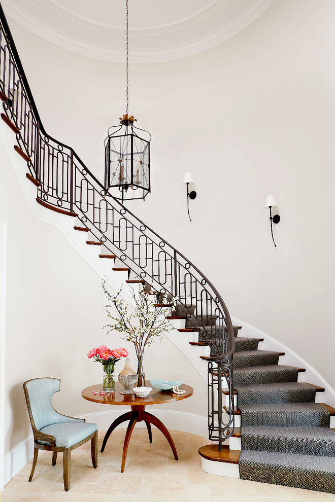 Пример оригинального дизайна: изогнутая лестница в классическом стиле с металлическими перилами, деревянными ступенями и крашенными деревянными подступенками