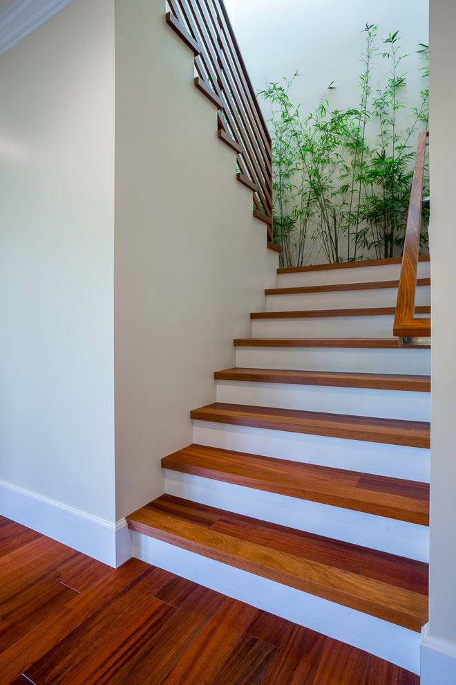 Foto de escalera en U tropical de tamaño medio con escalones de madera, contrahuellas de madera pintada y barandilla de madera