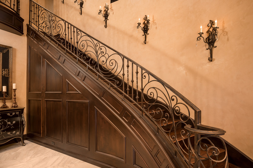 Foto de escalera curva clásica extra grande con escalones de madera, contrahuellas de madera y barandilla de metal