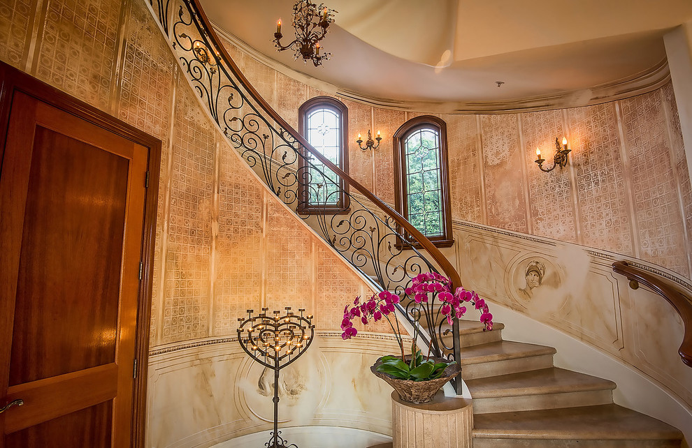 Пример оригинального дизайна: огромная изогнутая лестница в средиземноморском стиле с мраморными ступенями, подступенками из мрамора и перилами из смешанных материалов