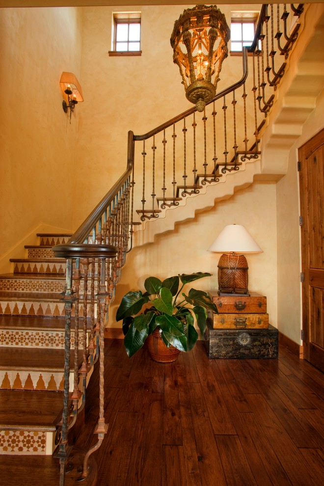 Modelo de escalera en L mediterránea grande con escalones de madera, contrahuellas con baldosas y/o azulejos y barandilla de varios materiales