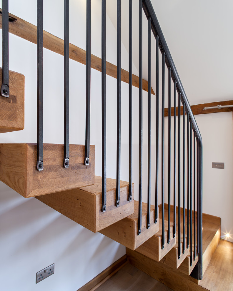 На фото: большая деревянная лестница на больцах в стиле кантри с деревянными ступенями и металлическими перилами